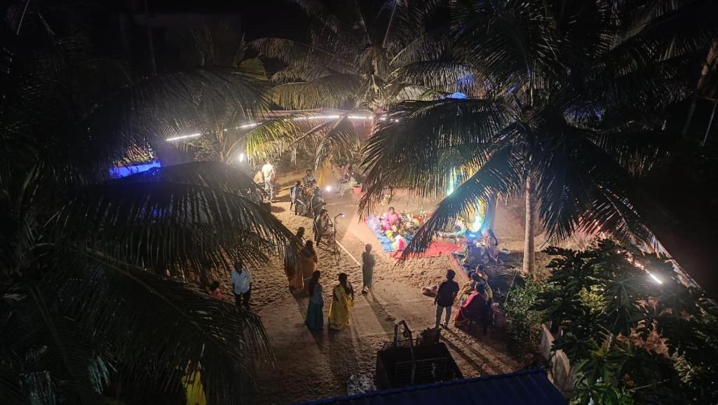 Baada Beach VT stay في Tadri: مجموعة من الناس تقف على الشاطئ في الليل