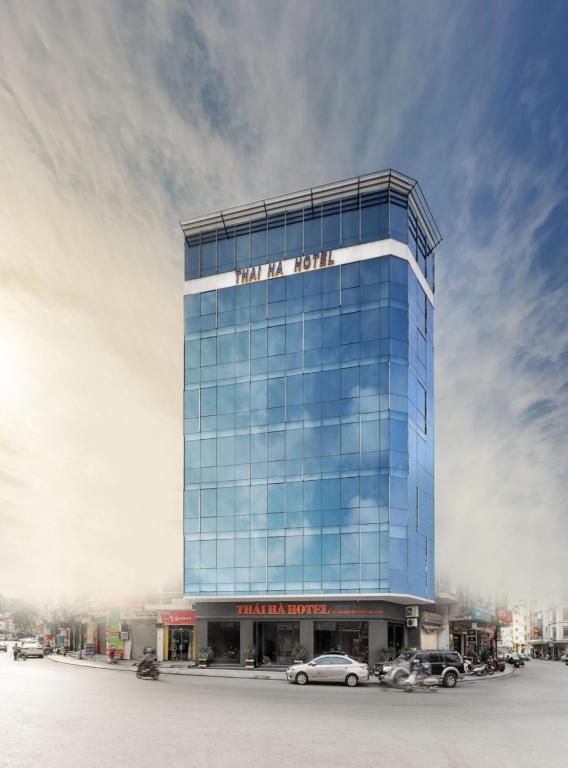 a tall glass building with cars parked in front of it at Thai Ha Hotel in Ha Long