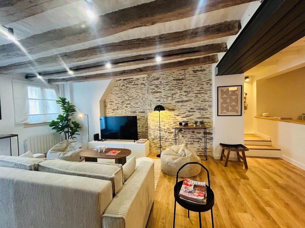 un soggiorno con un divano e un muro di pietra di Casa Bohème Chic ad Angers
