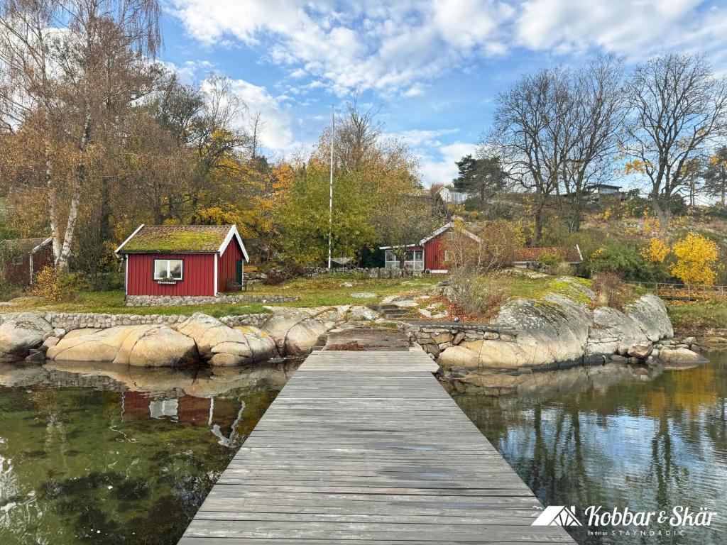 a bridge over a body of water with a red house at Dog-friendly cottage with boat & private jetty at Tjörn SE09170 in Krommeröd