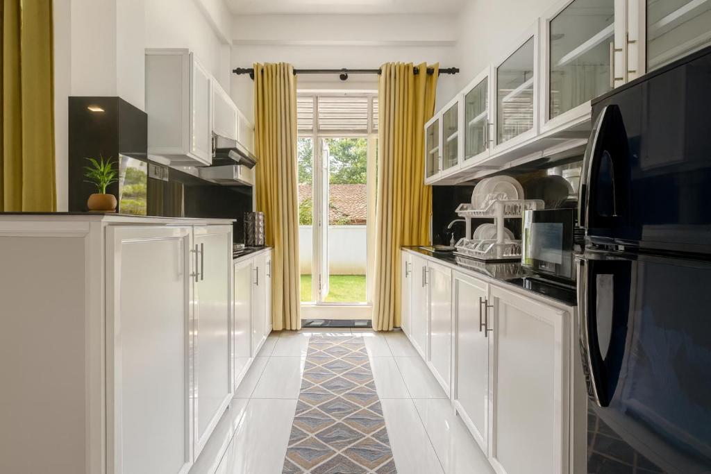 una cocina con armarios blancos y cortinas amarillas en Skyport Villa Katunayaka, en Katunayake