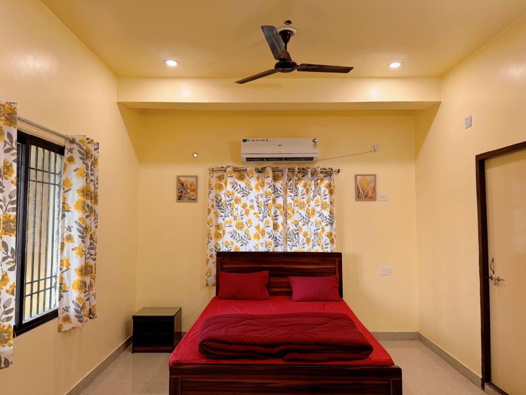 Schlafzimmer mit einem roten Bett und einem Deckenventilator in der Unterkunft Studio 401 Cityscape Retreat in Deoghar