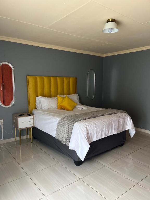 een slaapkamer met een groot bed met een geel hoofdeinde bij The Comfort Cottage in Saulspoort