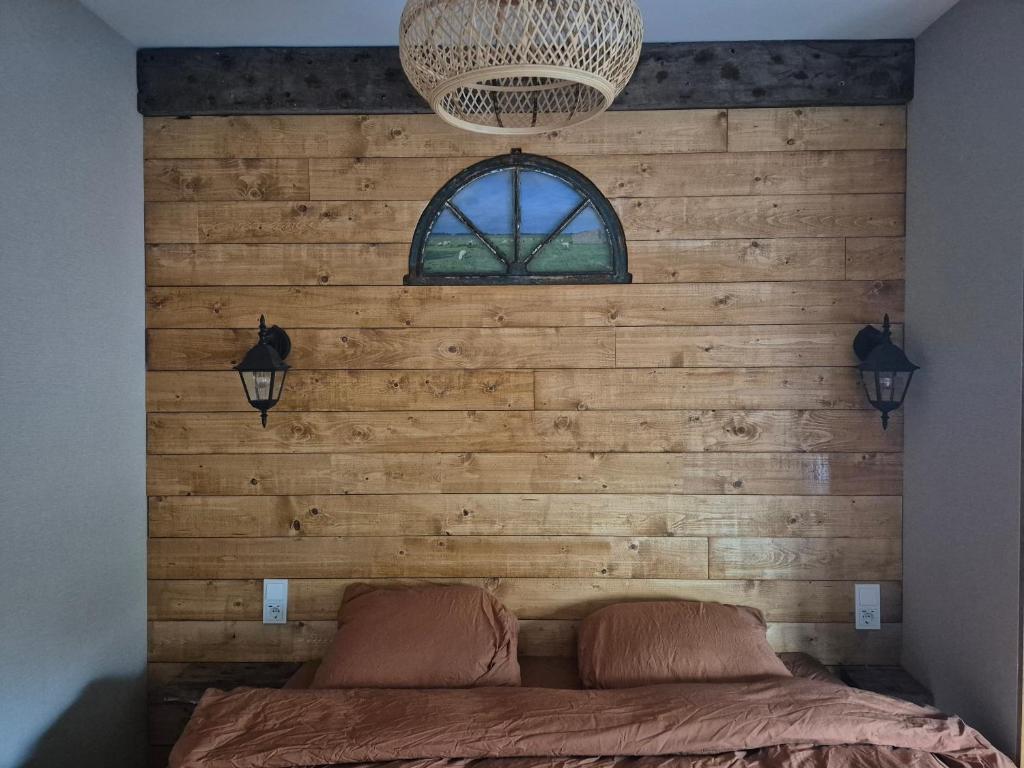 Un dormitorio con una pared de madera y una cama en B&B Lindehoeve Texel, en Den Hoorn