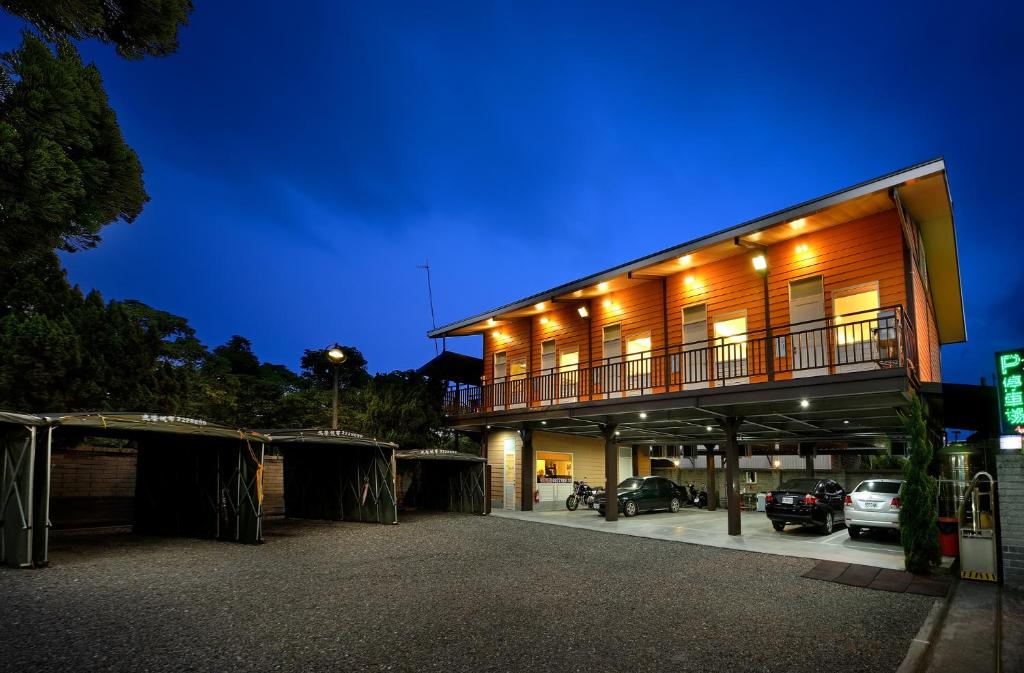 Un edificio con coches aparcados en un estacionamiento por la noche. en Jinge Guest House 集集金格民宿電動車充電站, en Jiji