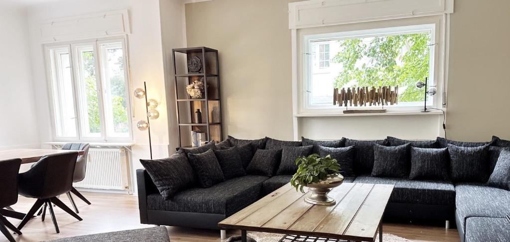 un salon avec un canapé noir et une table dans l'établissement Ferienwohnung Seelenruh, à Falkensee