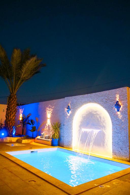 a swimming pool with a fountain in a building at Dar Ayline in Erriadh