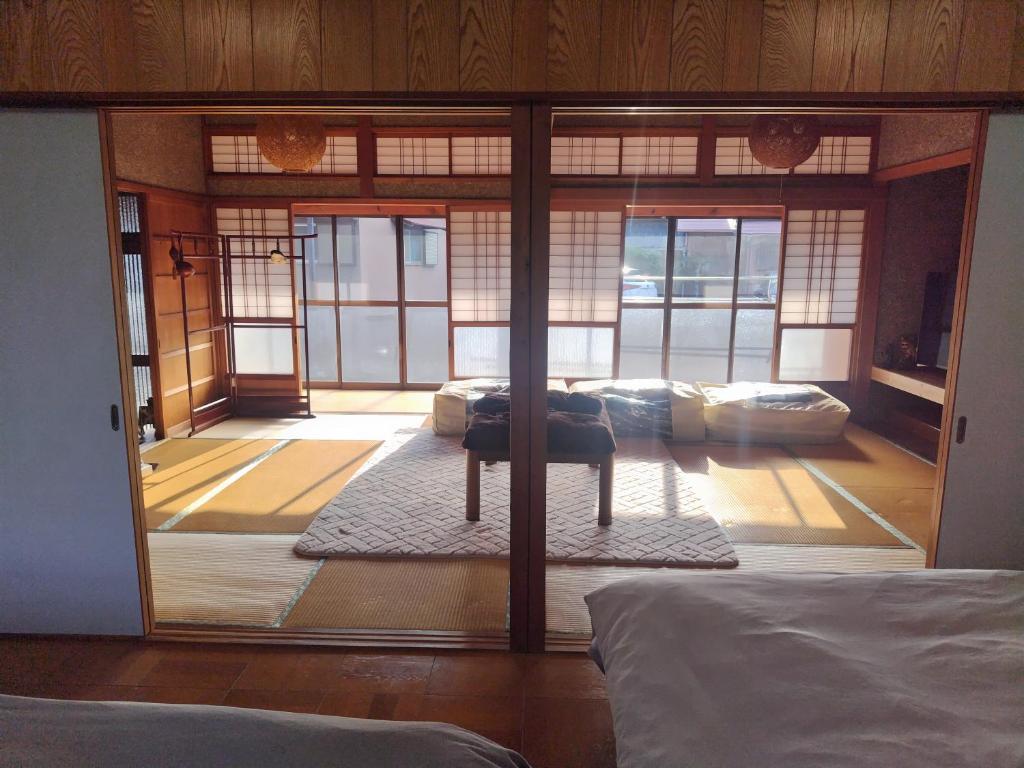 Habitación con una gran puerta de cristal que conduce a un dormitorio. en なぎさの宿 日本文化古き良き建物畳敷 大家族グループ利用 長期滞在ok駐車場無料 日本の真ん中Mie Suzuka Ise, en Tsu