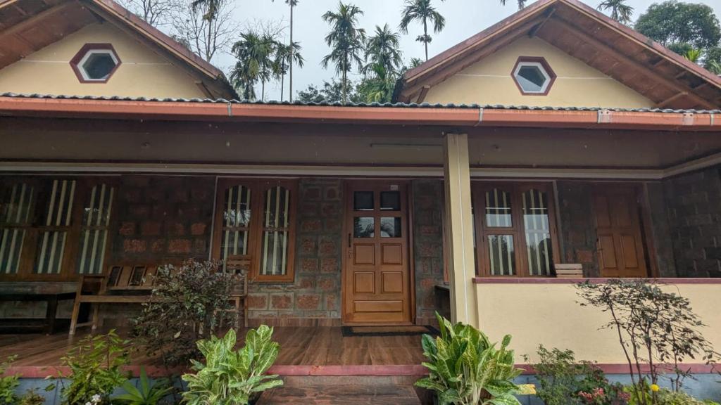 Halli Bailu Cottages في Somvārpet: منزل مع شرفة وباب