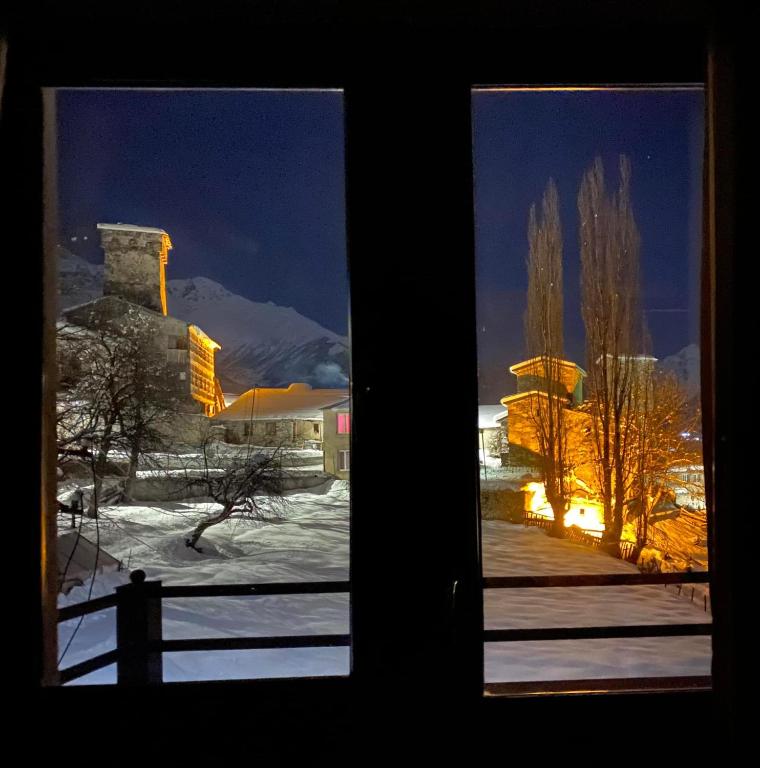 a window with a view of a snow covered yard at Roza Mountain View Guesthouse in Mestia