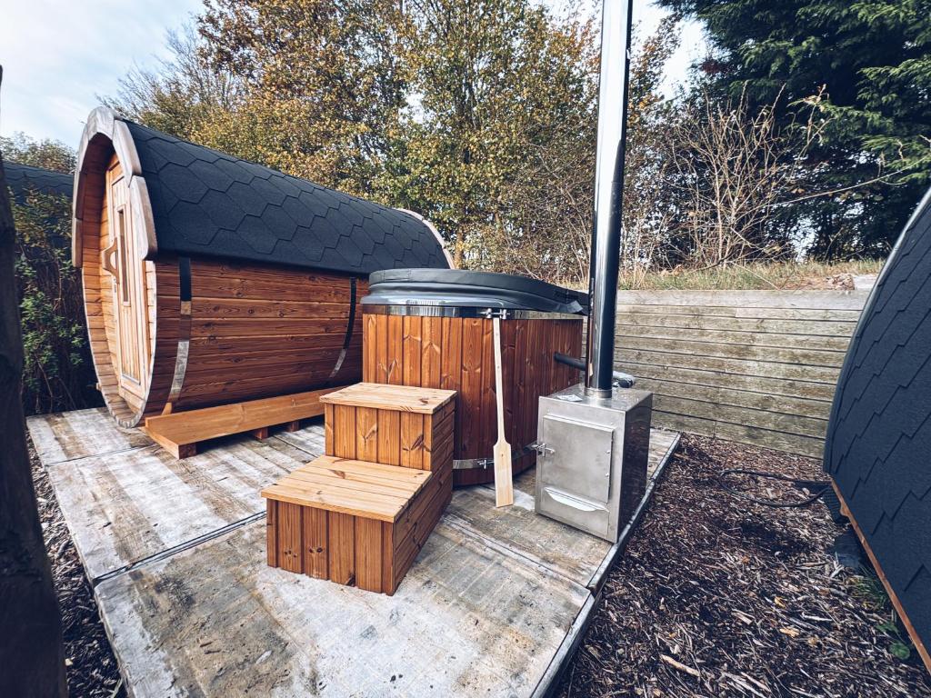 a wooden outhouse with a wood stove on a deck at Wellness Glamping Pod met privé Hottub & Sauna in Oudehornstercompagnie
