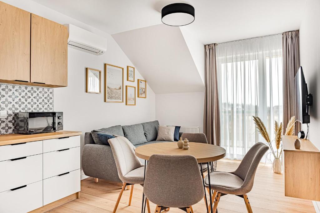 a kitchen and living room with a table and a couch at Cortaderia Haven - SPA - Basen, Jacuzzi, Sauna & Parking in Ustronie Morskie