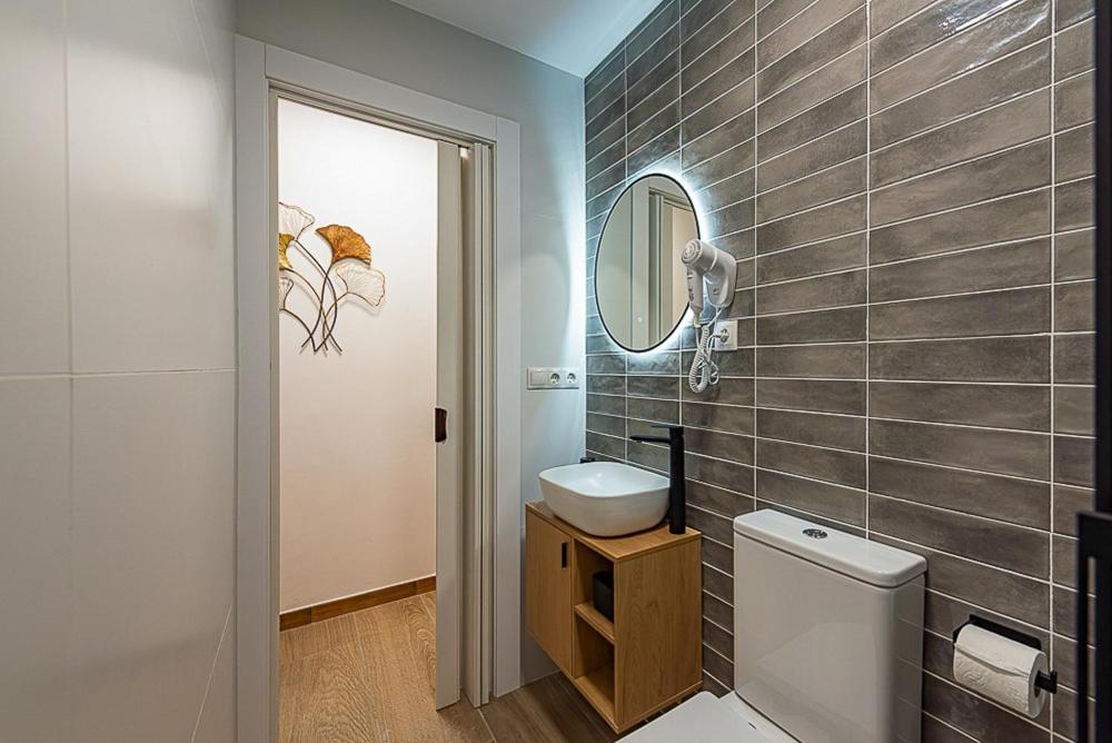 Un baño con inodoro, lavabo y espejo. en Black Lion, en Villena