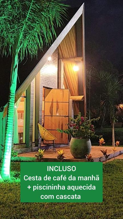 a house with a palm tree and a chair in front of it at Chácara Kioski - Suítes e Cabanas in Brotas