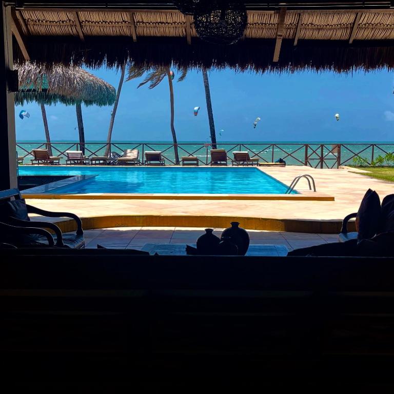 a swimming pool with chairs and the ocean in the background at Pé na Areia no Cumbuco - Eco Paradise 110 in Caucaia