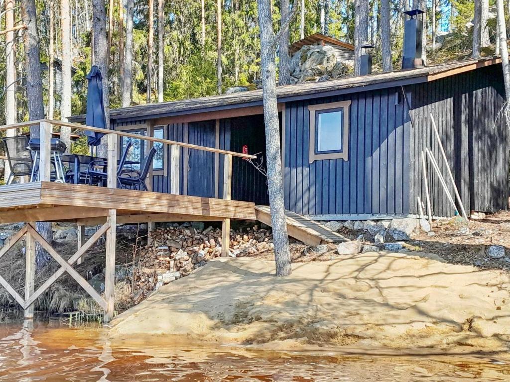 a blue cabin with a deck in the woods at Holiday Home Louhikko by Interhome in Houhajärvi