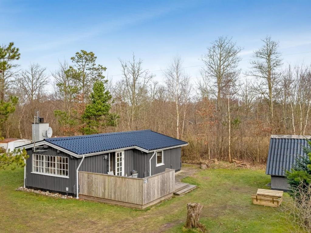 Un pequeño cobertizo gris con un porche en un patio. en Holiday Home Leandra - 11km from the sea by Interhome, en Dyreby