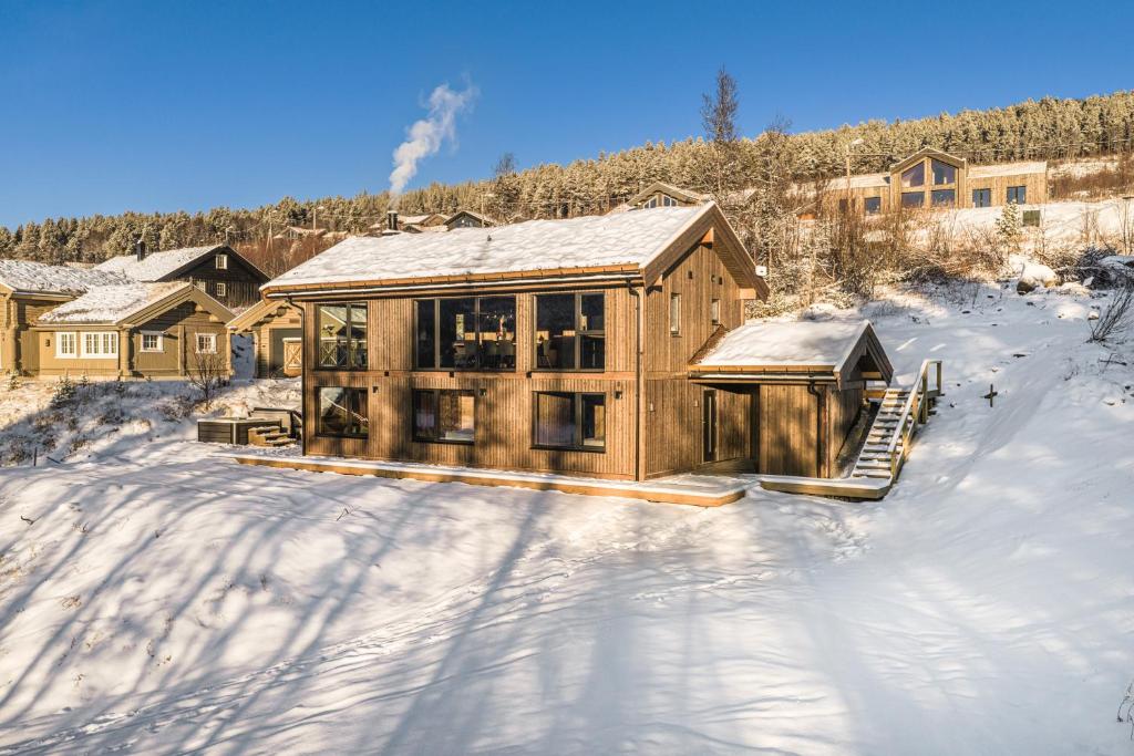 Una gran casa de madera en la nieve con nieve. en New luxury cabin in Geilo with hot tub, mountain views & ski access, en Lii
