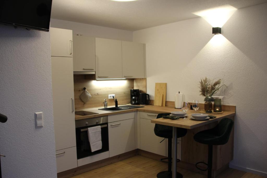 eine kleine Küche mit weißen Schränken und einem Tisch in der Unterkunft Das Atelier im Kalterbach in Bad Laasphe