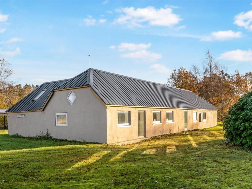 a house with a black roof on a grass field at Holiday Home Emelia - 4-2km from the sea by Interhome in Byrum