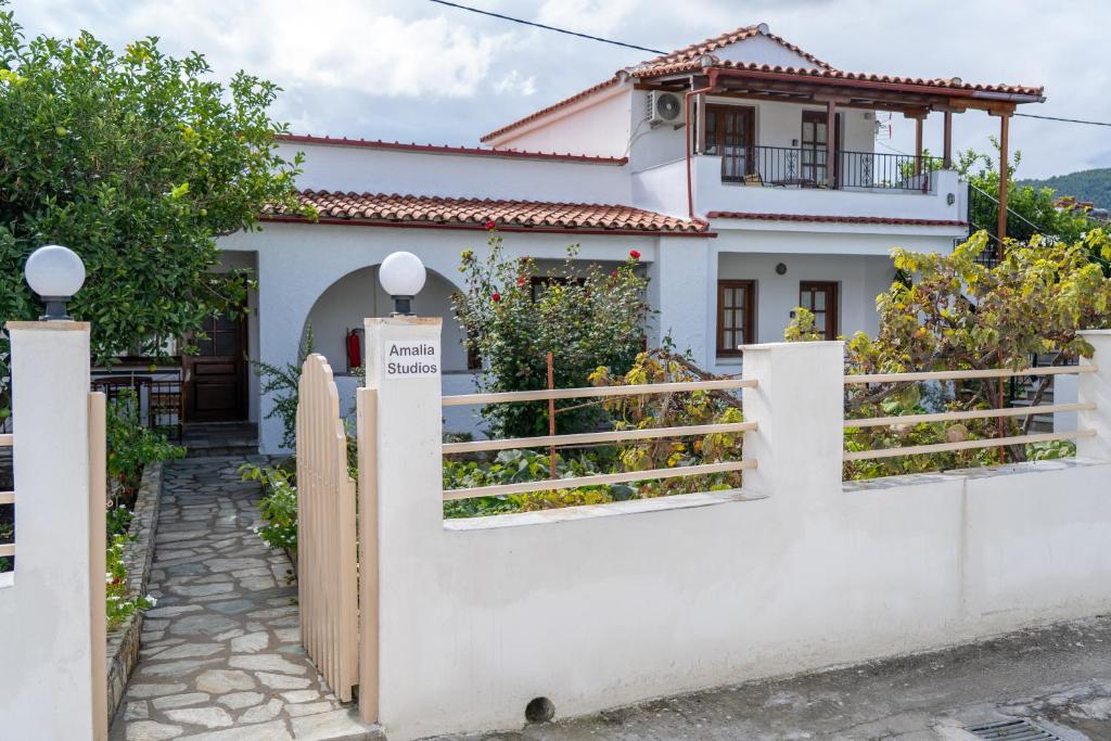 a white house with a gate and fence at Amalia Studios Skiathos in Skiathos Town