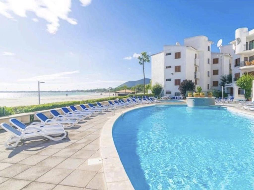 a swimming pool with lounge chairs and the beach at Apartment Carabela Chic by Interhome in Alcudia