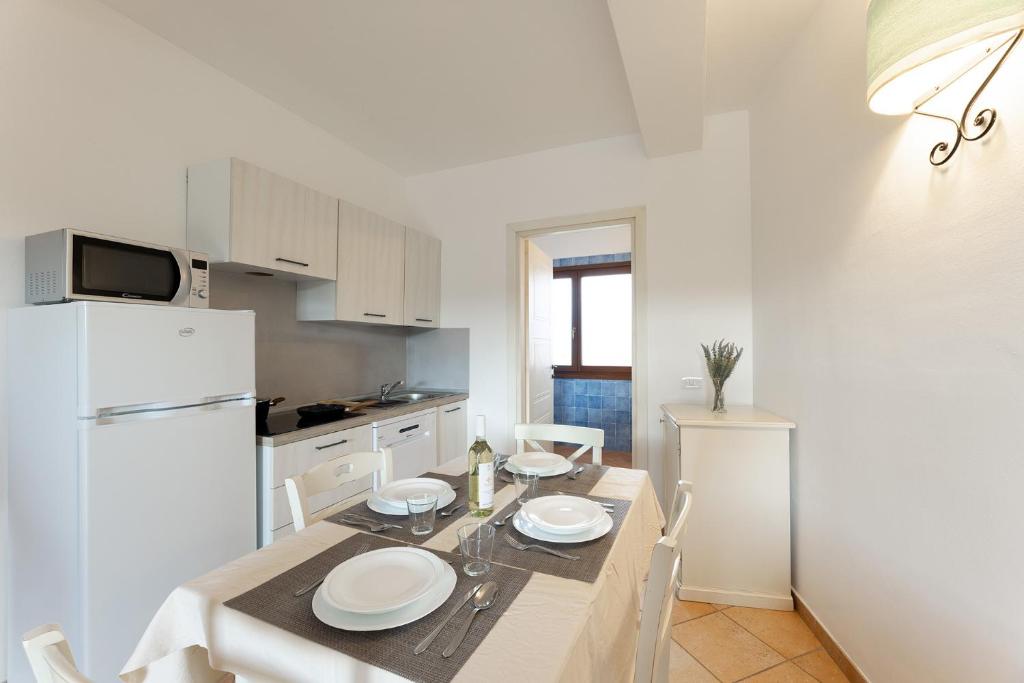 a kitchen with a table and a white refrigerator at Baia dei Mirti 4 people Apartment in Vignola Mare