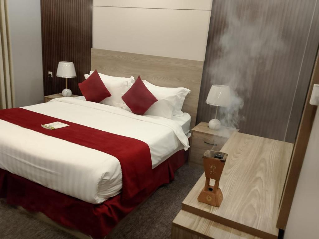 una habitación de hotel con una cama grande con almohadas rojas y blancas en راحتي هنا 7, en Riad