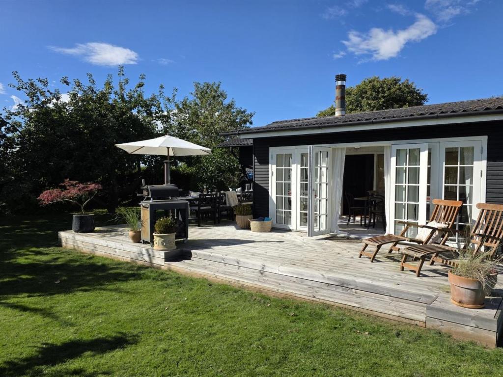 Holiday Home Yvette - 350m from the sea by Interhome في Hejlsminde: فناء مع كراسي ومظلة بجوار منزل