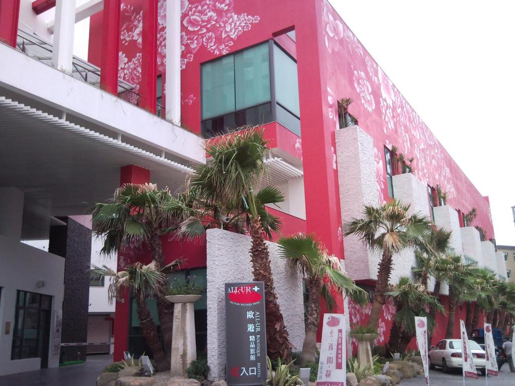 a red building with palm trees in front of it at All-Ur Boutique Motel - ChungLi Branch in Pingzhen