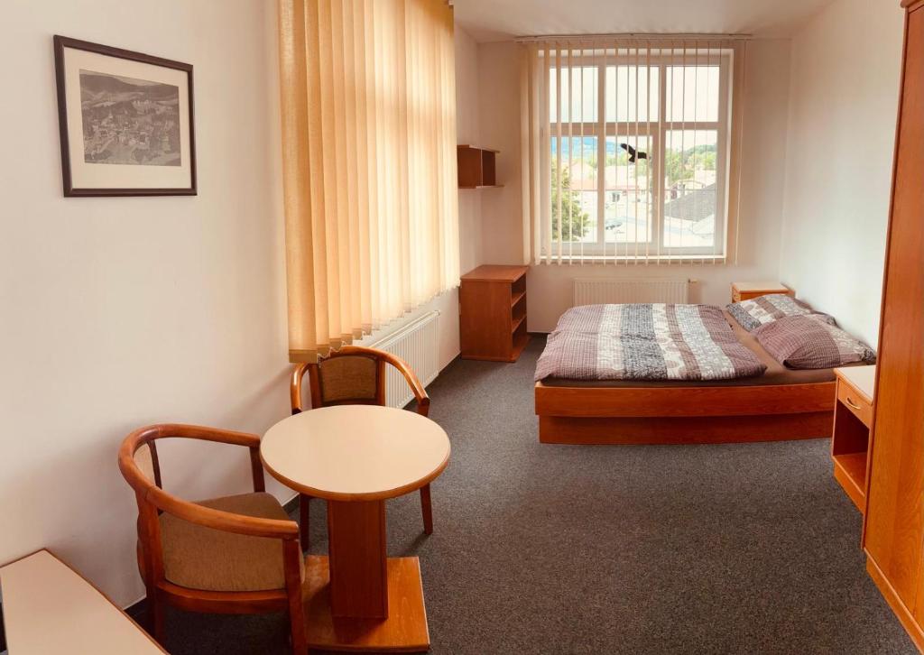 a bedroom with a bed and a table and a window at Self-Check Hostel Rico in Vrchlabí