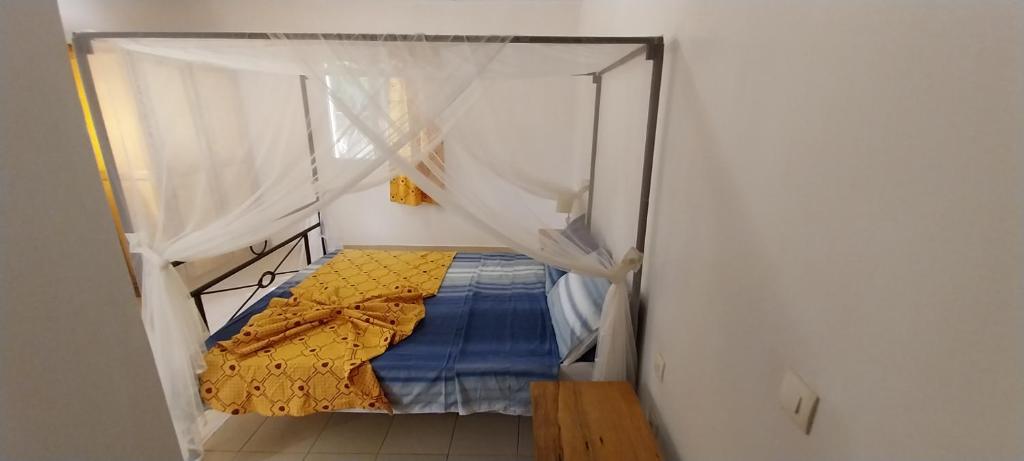 Le Ganalé في Warang: سرير صغير مع مظلة في الغرفة