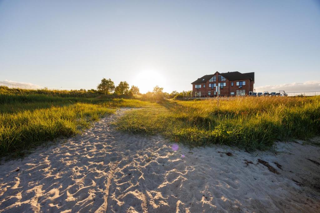 a house sitting on top of a beach with a dirt road at Bades Huk Marina Hotel in Hohen Wieschendorf