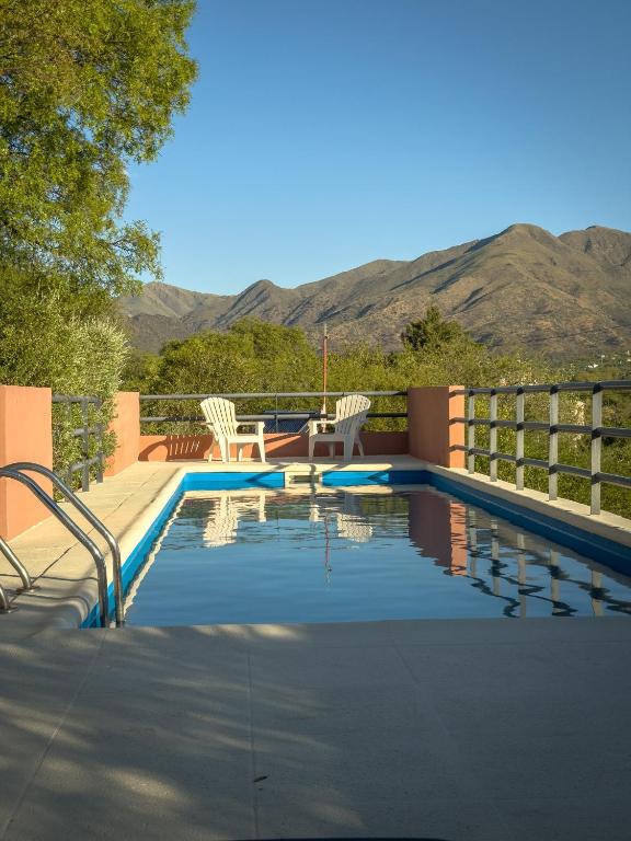 a swimming pool with chairs and mountains in the background at Aguas Claras in Capilla del Monte