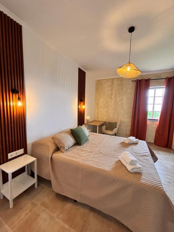 ein Schlafzimmer mit einem großen Bett und einem Tisch in der Unterkunft Casa de Campos AL in Angra do Heroísmo