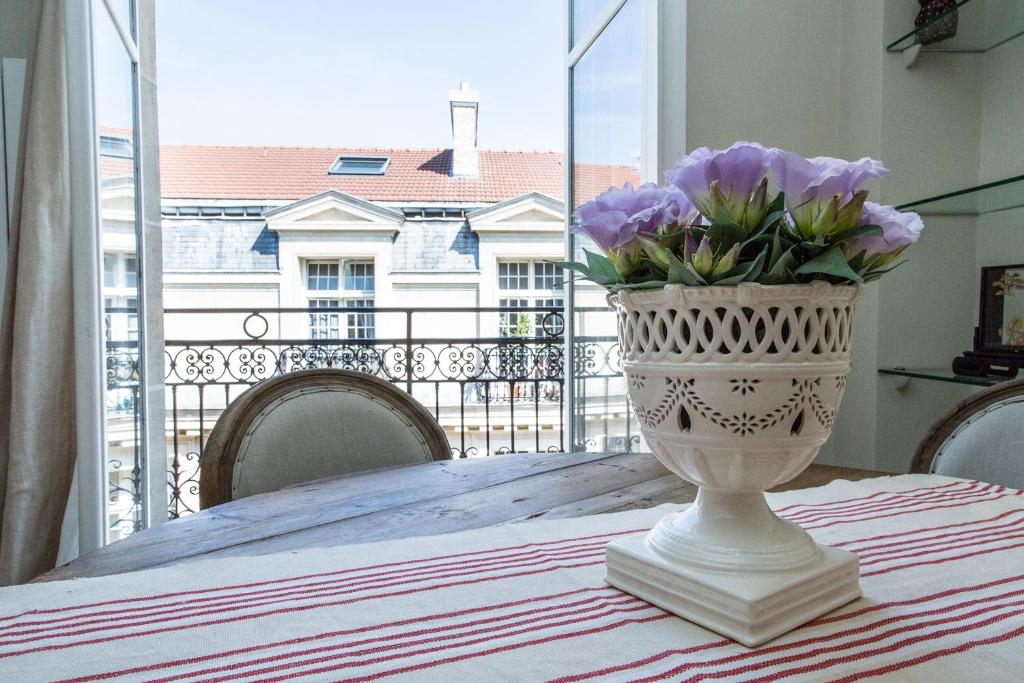 un vase rempli de fleurs violettes assises sur une table dans l'établissement Marais Centre Pompidou ID 233, à Paris