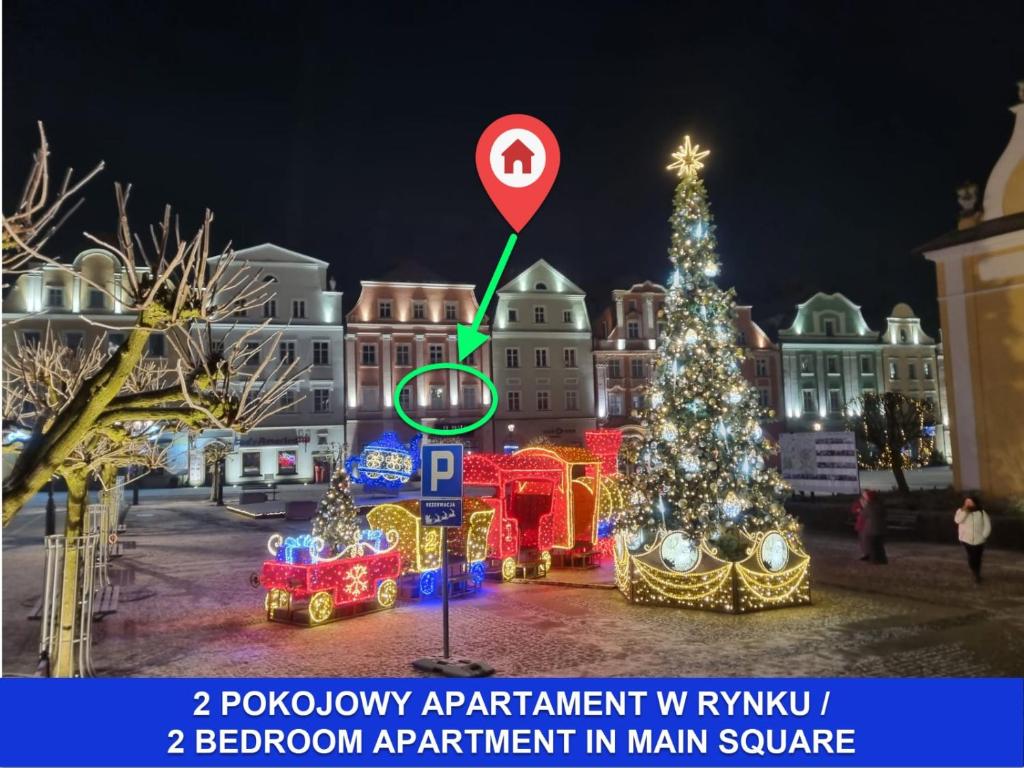 a christmas tree and a train in a city at night at Apartament Przy Starówce - Bella in Bolesławiec