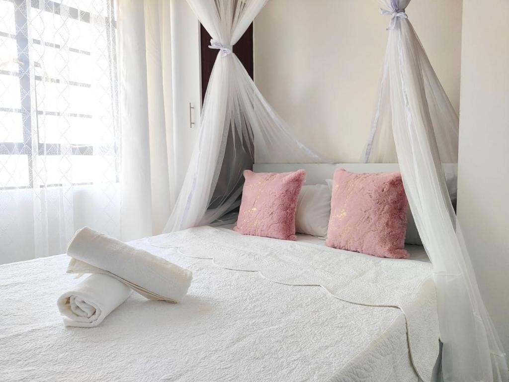 Un dormitorio con una cama blanca con almohadas rosas. en Makasembo furnished apartments one bedroom, en Kisumu