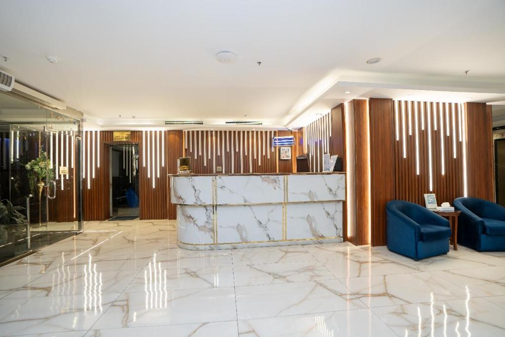 a lobby with a marble counter and blue chairs at فندق جوهرة المقام الحمراء in Jeddah