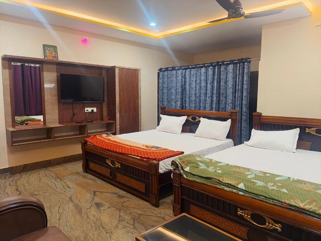 a hotel room with two beds and a television at Jaya SriRama Lodge in Bhadrāchalam