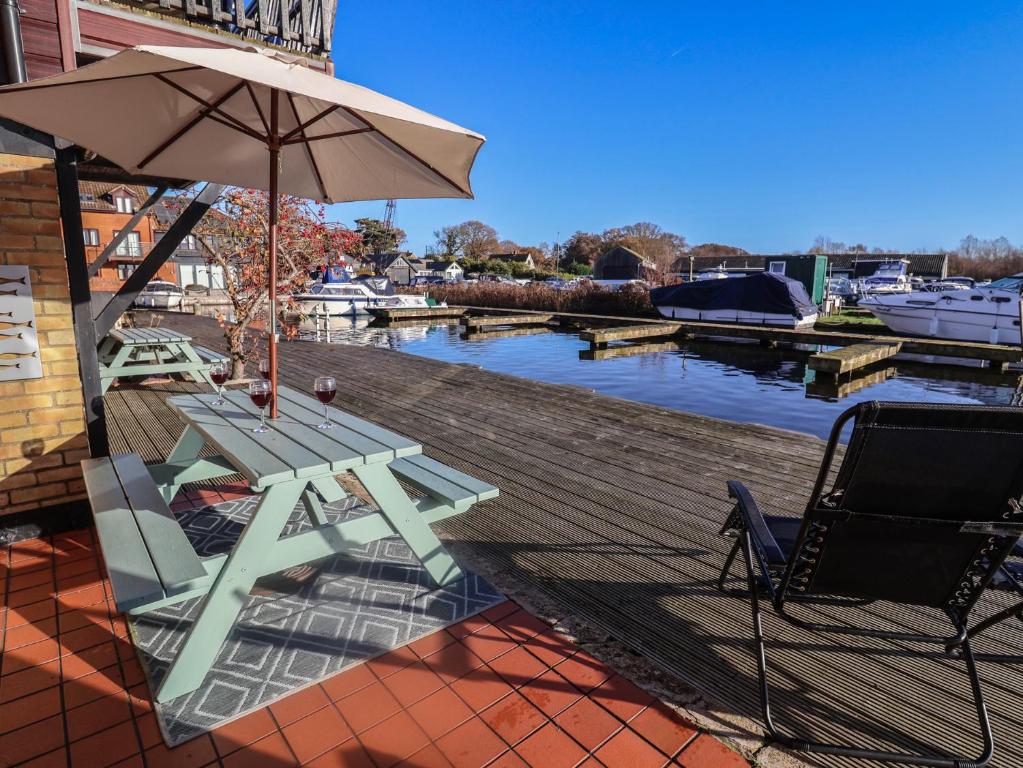 a picnic table and an umbrella on a deck at Daisy Lodge in Norwich