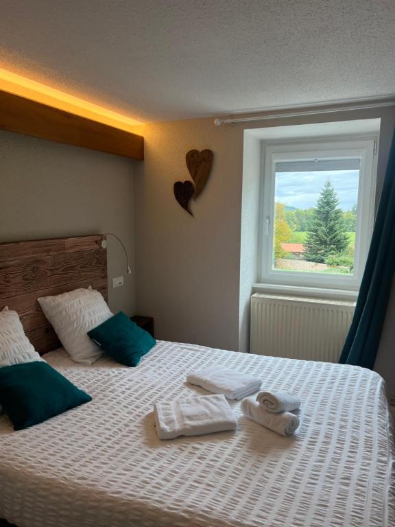 a bedroom with two towels on a bed with a window at Hôtel Restaurant Valneige in Mittlach