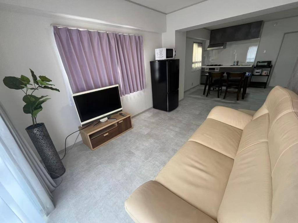ein Wohnzimmer mit Sofa und Fernseher in der Unterkunft Miya's Home 102-名駅まるまる貸切メゾン in Nagoya