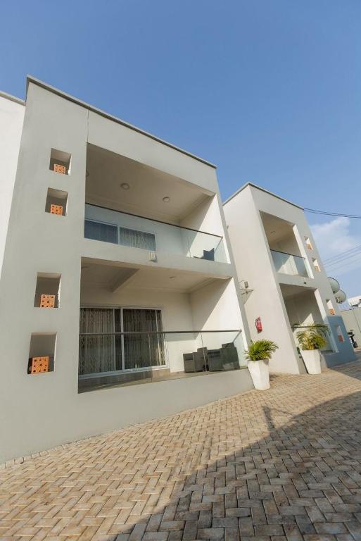 a large white building with a brick driveway at Maseru Apartments in Bawaleshi