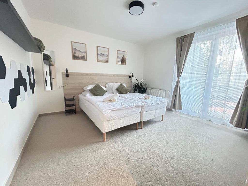 a white bedroom with a bed and a large window at Hotel Sport Houštka 