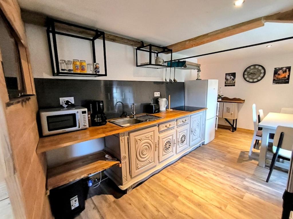 Le Dahlia - Jardin de Marie في Cerizay: مطبخ مع كونتر مع ميكروويف ومغسلة