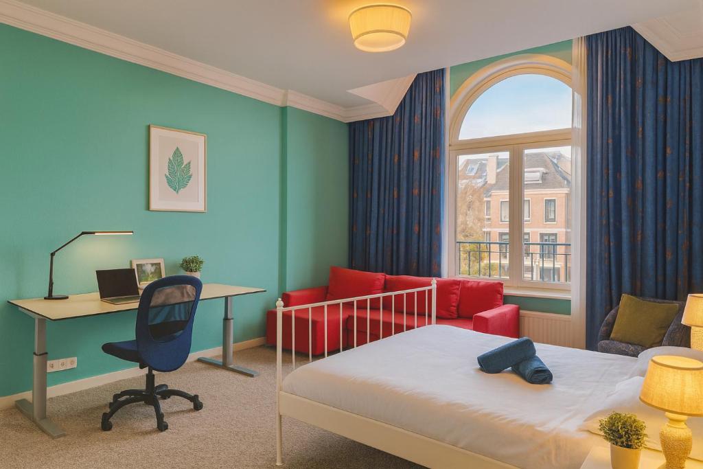 1 dormitorio con 1 cama, escritorio, 1 cama y 1 silla en Flora's Palace - The Hague Scheveningen, en La Haya