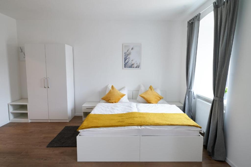 a white bedroom with a bed and a window at WeinlandMotel in Ebenthal