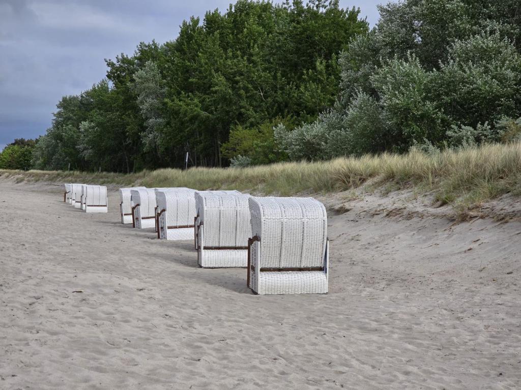 a row of white chairs sitting on the beach at Strandresidenz Wittower Heide in Glowe