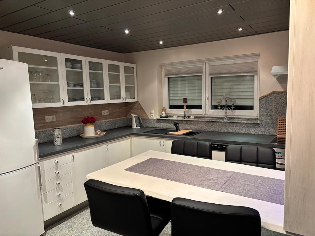 Cozy 2-room non-smoking apartment في بينسهايم: مطبخ مع دواليب بيضاء وطاولة مع كراسي سوداء